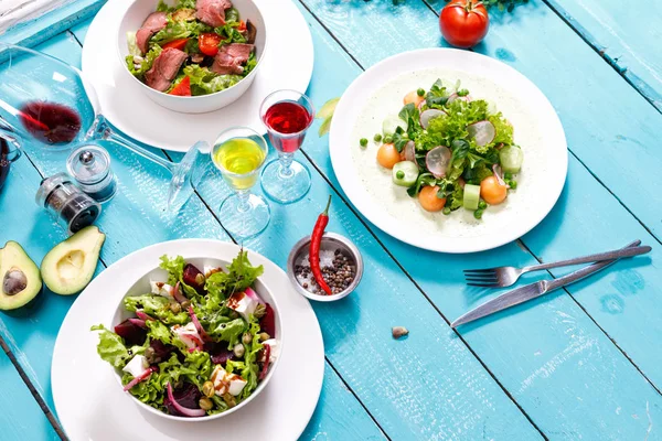 Greek salad background. Bowl with fresh greek salad, tomatoes, olives, olive oil on wooden table. Space for text. Top view. Traditional greek dish. Ingredients for making salad. Mediterranean diet