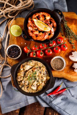 Domates soslu büyük karides, krema soslu mantar, jülyen, şampiyon, ahşap masa arkasında yemek pişirme ürünleri.