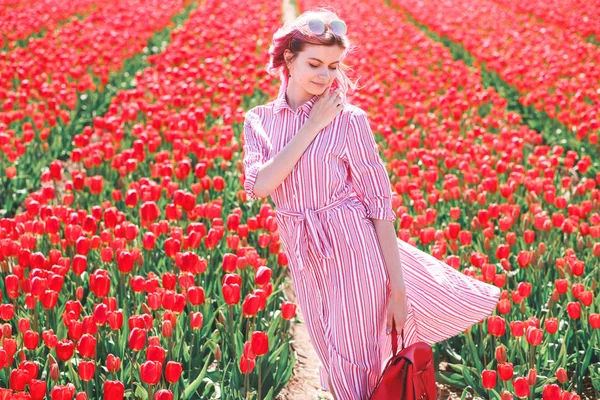 Усміхнена дівчина-підліток проходить через поле тюльпанів — стокове фото
