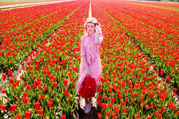 Sorrindo adolescente menina caminha através de campo de tulipa — Fotografia de Stock