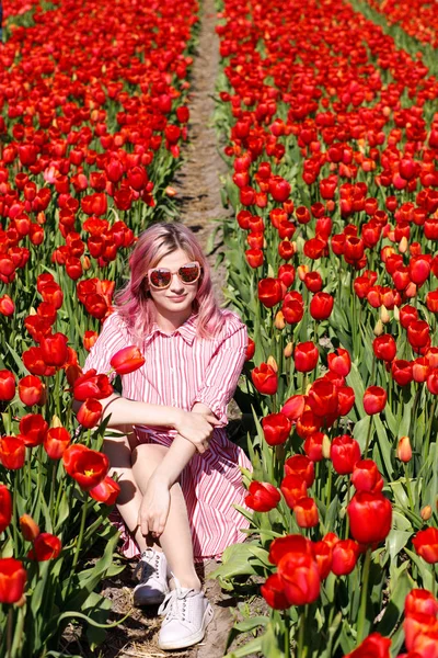 Smiling teenage girl walks through tulip field — Stock Photo, Image