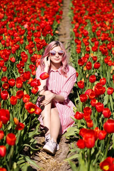 Smiling teenage girl walks through tulip field — Stock Photo, Image