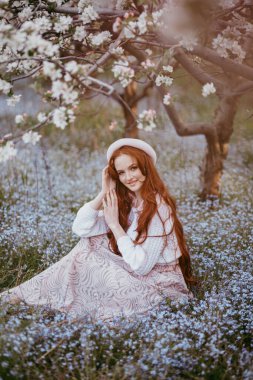Baharda çiçek açan elma bahçesinde uzun saçlı bir esmer.