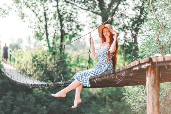 Uma Menina Senta Uma Ponte Sobre Rio Cercado Por Folhagem — Fotografia de Stock