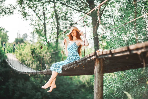 Uma Menina Senta Uma Ponte Sobre Rio Cercado Por Folhagem — Fotografia de Stock