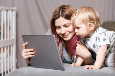 Evde kal, annem dizüstü bilgisayarla uzaktan çalışıyor, çocuğuna bakıyor. Doğum iznine ayrılmış genç bir anne bebekle bağımsız olarak çalışmaya çalışıyor. Kapat.