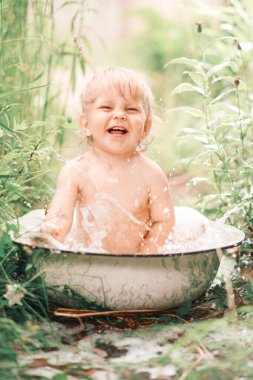 Güneşli bir yaz günü. Sevimli küçük bir çocuk yeşil bir çimenlikte banyo yapıyor. Suyla ıslanmış, su sıçrıyor ve gülüyor..