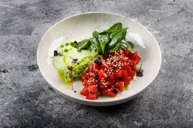 Enfes balık tartar çiğ ton balığı filetosu, yeşillikler beyaz bir tabakta.