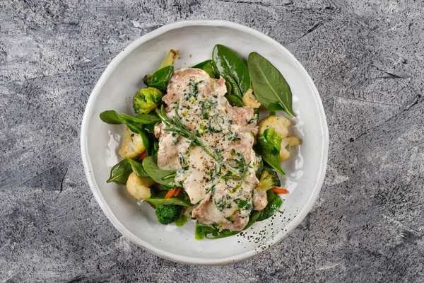 chicken in Cream sauce with Broccoli ,cauliflower,Basil and rosemary on a white plate