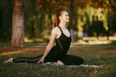 Güzel bir kız doğasında yoga yapıyor. Açık hava eğitimi ve refah için ideal.