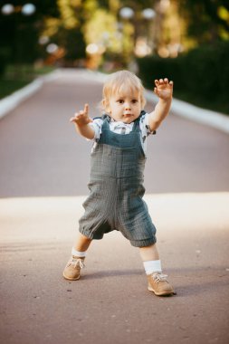 Muslin tulumu giymiş mutlu bir çocuk yeşil çimlerin üzerinde dinleniyor. piknik