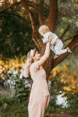 Bir anne oğlunu bir yaz günü bir parkta kollarına alır.