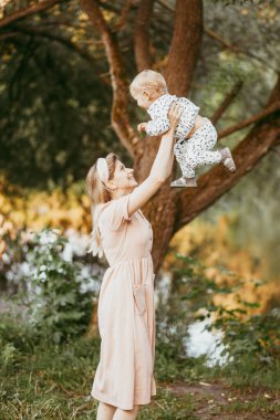 Bir anne oğlunu bir yaz günü bir parkta kollarına alır.