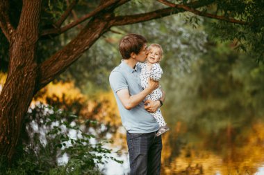 Mutlu aile babası ve oğlu parkta yürüyor.