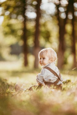 Bir yaz günü, gün batımında, bir tarlada eski bir tulum giymiş küçük sarışın bir çocuk..