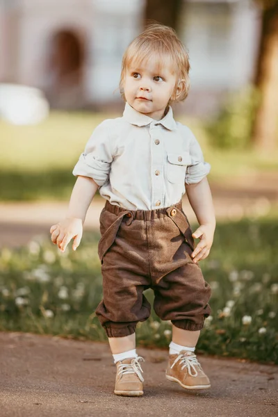 夏の日の日没時に畑でヴィンテージのジャンプスーツを着た小さなブロンドの男の子 — ストック写真