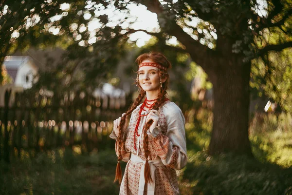 白と赤の刺繍のスーツで長いブロンドの髪と茶色の目を持つ美しいスラブの女の子は 木製のフェンスで立っています ウクライナ地域の伝統的な服 夏の日 — ストック写真