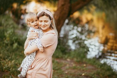 Bir anne oğlunu bir yaz günü bir parkta kollarına alır.