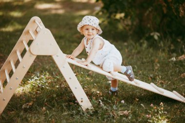 Çocuk spor kompleksinde çocuk kaydırağında spor yapıyor. 1,5 yaşında bebek jimnastik merdivenlerinden çıkıyor. Erken çocukluk gelişimi. Yaşam tarzı etkinliği