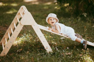 Çocuk spor kompleksinde çocuk kaydırağında spor yapıyor. 1,5 yaşında bebek jimnastik merdivenlerinden çıkıyor. Erken çocukluk gelişimi. Yaşam tarzı etkinliği