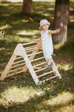 Şirin çocuk, ahşap spor kompleksi merdivenlerinde jimnastik yapıyor. Çocuk sporları egzersizleri. Çocukların beden eğitimi