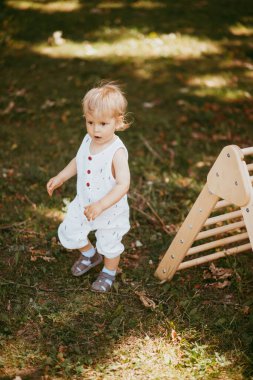 Şirin çocuk, ahşap spor kompleksi merdivenlerinde jimnastik yapıyor. Çocuk sporları egzersizleri. Çocukların beden eğitimi