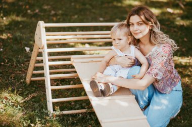 Annesinin yardımıyla bir spor kompleksinde jimnastik yapan sevimli bir çocuk. Çocuk sporları egzersizleri. Çocukların evde beden eğitimi