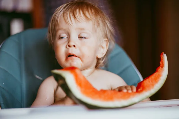 幸せな赤ちゃん男の子食べるスイカで彼の高い椅子に彼の家 — ストック写真