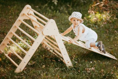 Çocuk spor kompleksinde çocuk kaydırağında spor yapıyor. 1,5 yaşında bebek jimnastik merdivenlerinden çıkıyor. Erken çocukluk gelişimi. Yaşam tarzı etkinliği