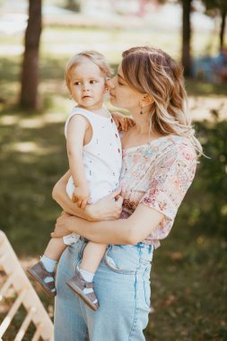 Genç bir anne, güzel bir yaz parkında gülümseyen bir yüzle oğluna sarılıyor. Aile bir ağacın altında dinleniyor, birlikte eğleniyor..