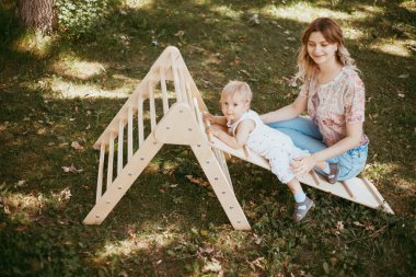 Annesinin yardımıyla bir spor kompleksinde jimnastik yapan sevimli bir çocuk. Çocuk sporları egzersizleri..