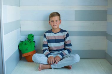 Handsome Young Boy wearing cozy pajamas Playing with His english funny bull Dog and enjoy life time weekend hanging each other with love and tender. Cactus toy. clipart