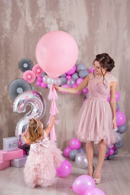 Anne ile kızı kutluyor aile olay her ikisi de kafasına altın taç giyen pembe havadar süslü elbiseler giymiş. Stüdyo ateş yumuşak yumuşak pastel renkler güzel ailenin