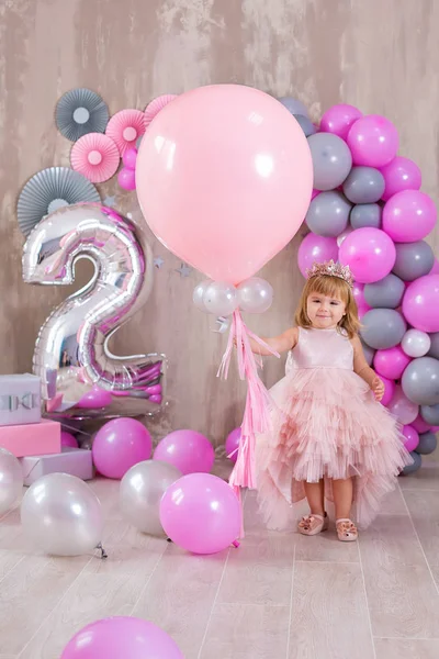 Linda Niña De 1-2 Años De Edad Sentado En El Piso Con Globos De Color Rosa  En La Habitación Sobre Blanco. Aislado. Fiesta De Cumpleaños. Celebracion.  Feliz Cumpleaños Bebé, Niña Con El