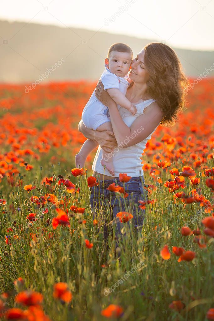 Outdoor portrait. Young mother and her daughter enjoy life time together on a poppy field . Concept of love and happy family. Poppy meadow.