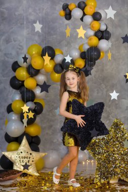 Film süper star kız model altın yıldız ve renkli baloons papyon parlayan ile şık altın havadar elbise giyen ile stüdyo çekimleri poz. Süper star yastık deisigned fotoğrafçı tarafından