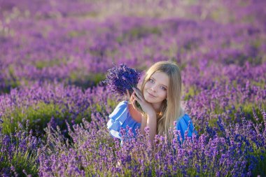 Güzel sarışın Bayan model lavanta alan üzerinde gülümseyen keyfini yaz günü buket çiçek ile havadar beyaz elbise