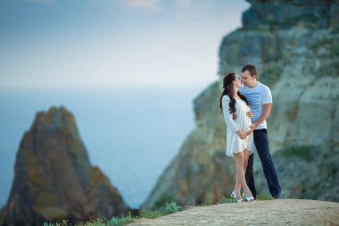 Arka plan olarak mavi deniz manzaralı üzerinde poz bekliyor bebek güzel genç çift.