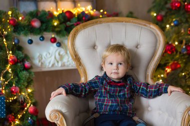 Bir şekilde dekore edilmiş Studio çatıda oturan ve Noel ile oynarken küçük sarışın çocuk portresi sunuyor ve kutular. Arka plan üzerinde kış orman, ağaçlar ve kar etkisi dekorasyon. Noel kavramı.