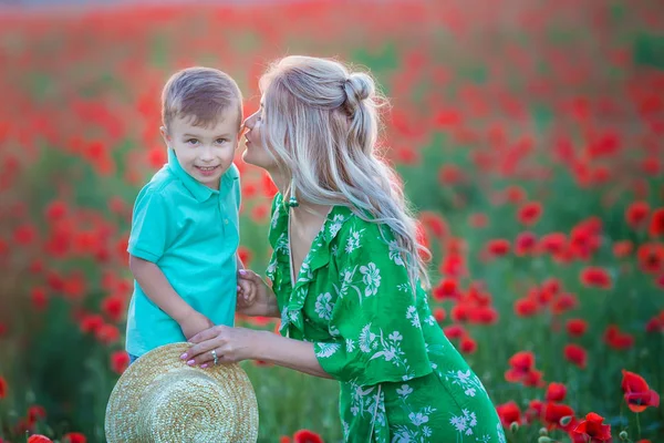 母亲与儿子在罂粟享受生活在日落 快乐的家庭暑假 漂亮的黑发 长着健康的头发抱着小男孩 无忧无虑的年轻妈妈过红场 乡村景观 — 图库照片