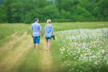 Romantik Çift sarılma ve daysy çiçekler ile sıcak bir alanda taze hava nefes