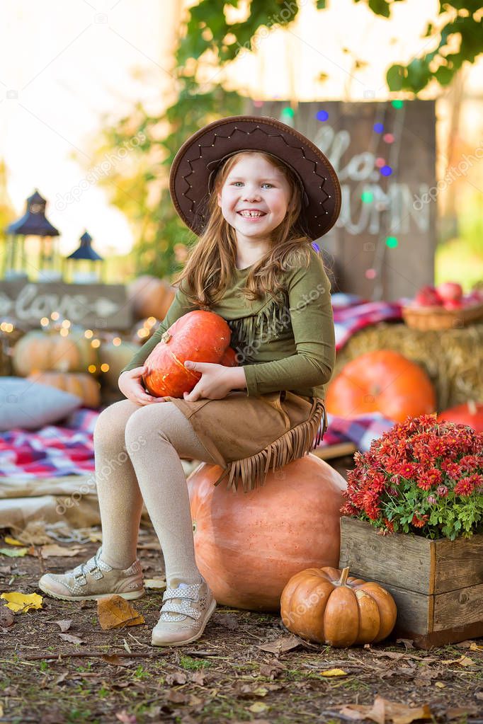 happy child girl with pumpkin outdoors in halloween.