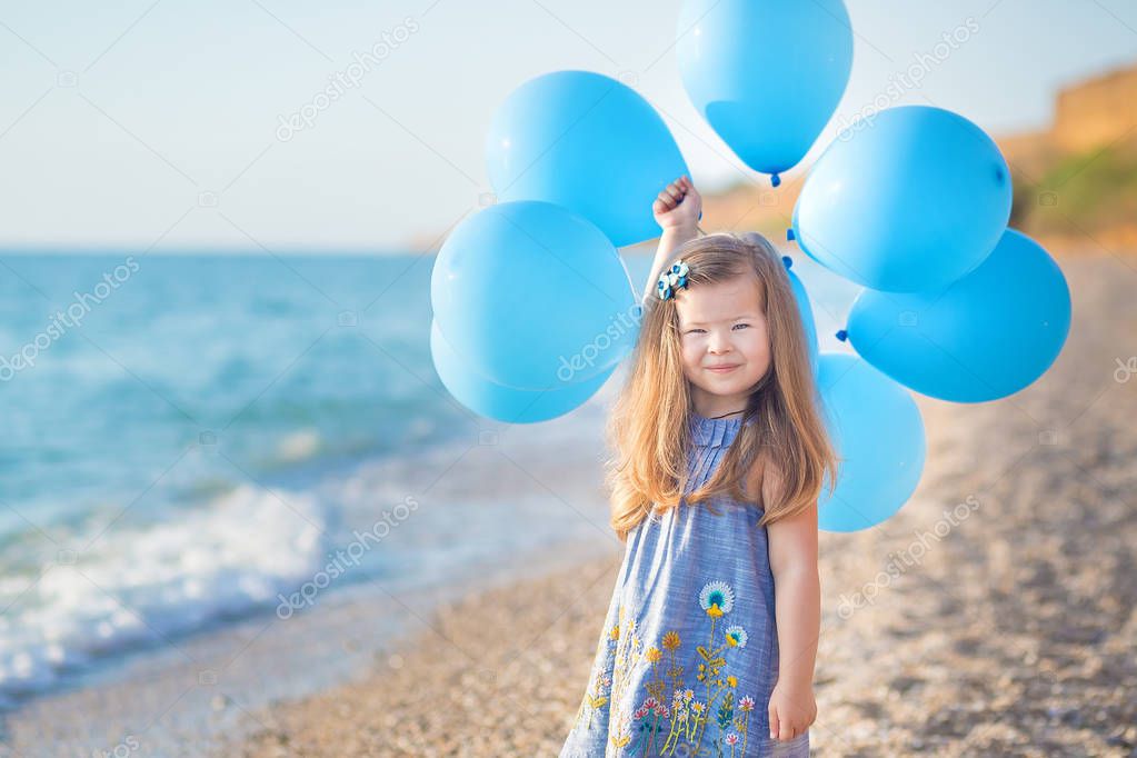 Cute girl with balloons posing on beach of ocean sea coast with sandy rocky land , a holiday, a sea trip.