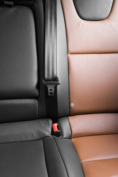 Часть черного кожаного сиденья автомобиля с акцентом на красный замок ремня безопасности
