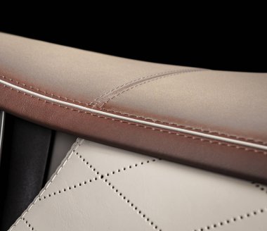 Dikişe odaklı kırmızı ve beyaz delikli deri araba koltuğu parçası.