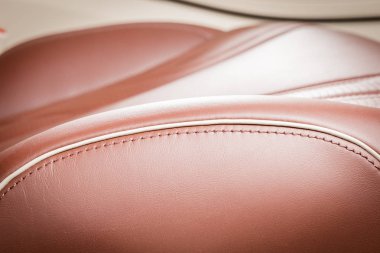 Lüks arabanın içinde dikişli kırmızı delikli deri sürücü koltuğu.