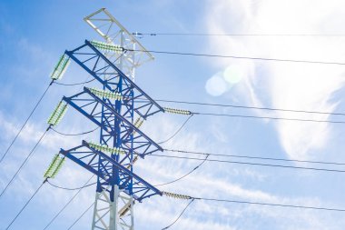 Mavi gökyüzüne ve bulutlara karşı yüksek voltajlı elektrik direkleri, elektrik hattı, elektrik direği.