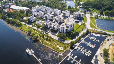 Nehir kenarındaki parktaki binaların hava aracı görüntüsü.