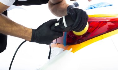 Adam, modern beyaz bir arabanın arka farlarını cilalıyor. Yakın çekim görünümü