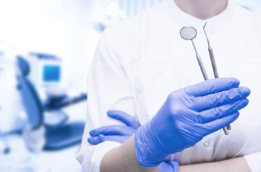 Tıbbi diş kliniğinde diş aletleri tutan eldivenli dişçi elleri